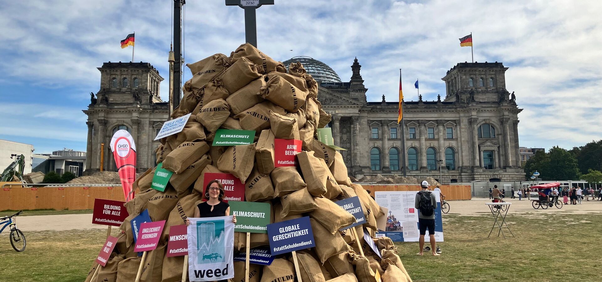 Erlassjahr-Aktion vor dem deutschen Reichstagsgebäude: Verena Kröss und ein symbolischer Schuldenhaufen Protest mit Schuldensäcken vor dem deutschen Reichstagsgebäude für eine bessere internationale Finanzarchitektur