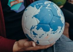 Ein fair produzierter Lederball wird von einer Multiplikatorin gehalten