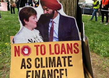 Demoplakat auf dem Kristalina Georgieva und Ajay Banga zu sehen sind mit der Aufschrift No to loans as climate finance